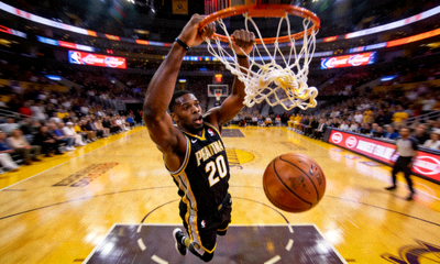 NBA赛场高光扣篮瞬间，篮球在空中被双手灌入篮筐